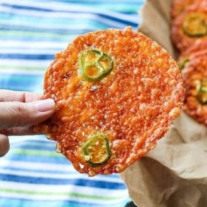 Round, crispy cheese crackers, fricos, 2-ingredient jalapeno popper crisps in paper bag, blue white and green tea towel