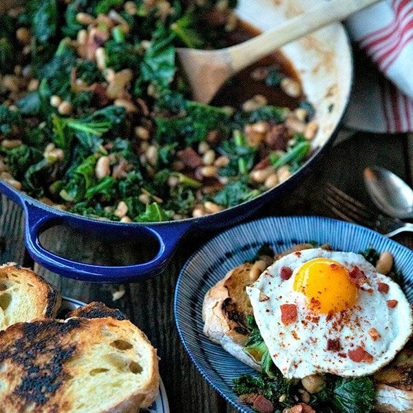 Tender beans and greens, caramelized onions, savoury bacon, sliced garlic, smoked paprika, and a hint of spice, star in this one-pot, low cost, crowd-pleaser served over indulgently thick slices of crunchy-edged, pan toasted garlic bread.