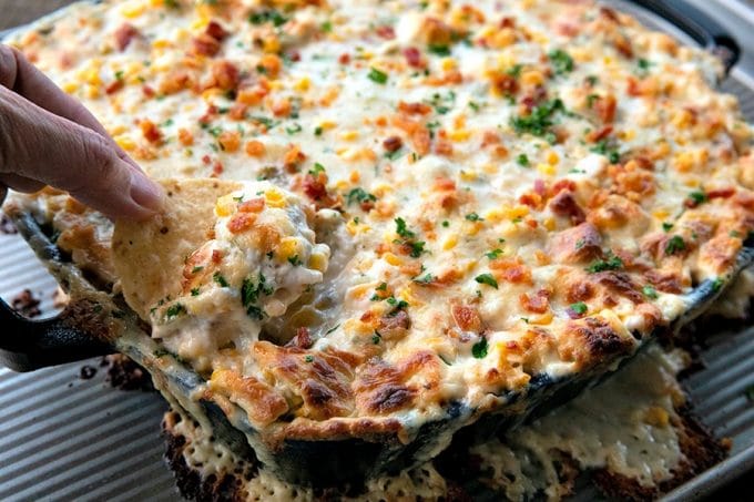 Hot corn dip is chock full of sweet corn, tender chicken, crispy, smoky bacon, hatch chiles, and green onions in a bubbling, creamy, ranch cheese sauce.