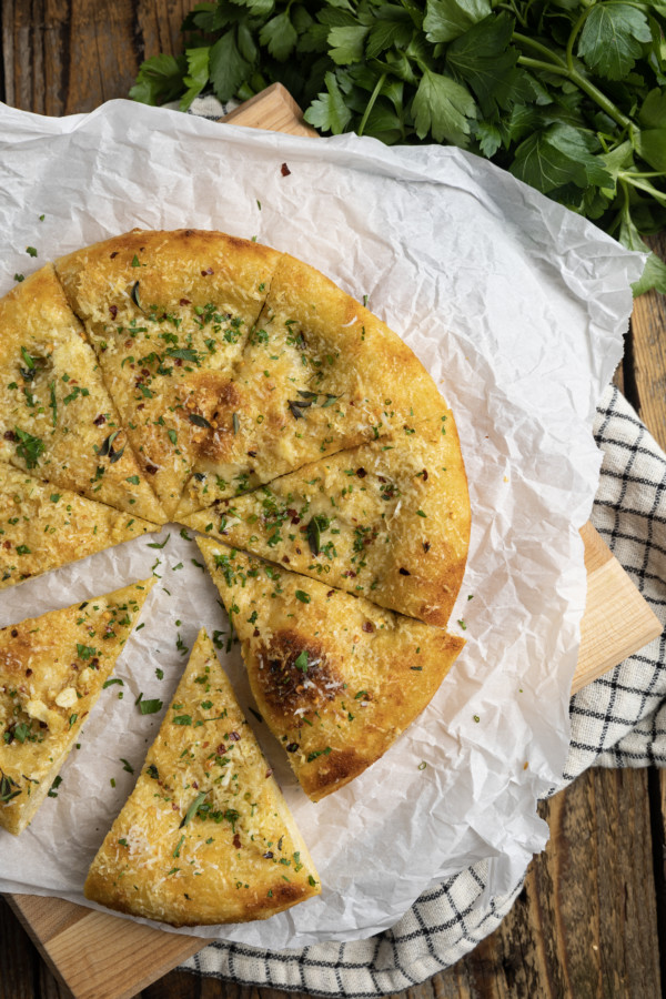 With its blistered, crispy crust and utterly irresistible aroma, Garlic Pizza is proof that the simplest things are often the best. You’ll find yourself turning to this deeply browned, super savoury pizza -made from simple ingredients that you likely have on hand already- more often than you can imagine. Garlic pizza is perfection in its simplicity. It’s just pizza dough brushed with homemade garlic oil, sprinkled with parmesan cheese, and a pinch of red pepper flakes.