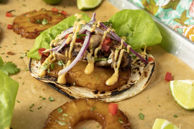 Make taco nights magical with jerk chicken tacos! Fresh lettuce leaves stacked on charred tortillas are piled high with juicy jerk chicken, grilled pineapple slices, diced bell peppers, thinly sliced onions, a drizzle of sauce or spoonful of mango salsa.