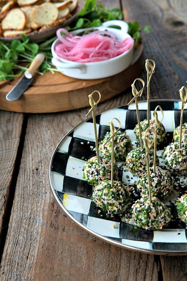 These gorgeous little two-bite, miniature cheese balls are dressed up with smoked salmon, chives, and everything bagel seasoning and taste like New York City when served with bagel chips, pickled red onions, and capers.