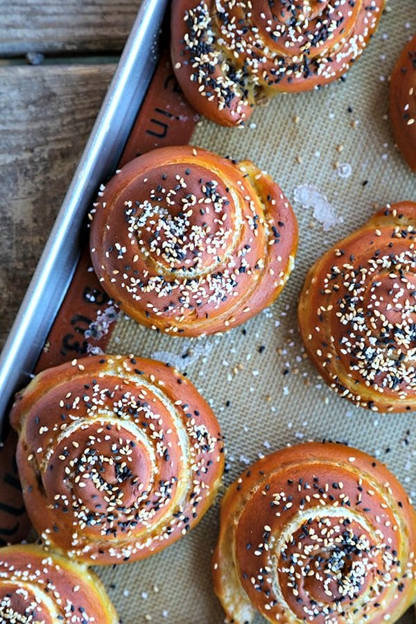 Soft pretzel rolls for sandwiches, silpat, half sheet pan, rustic wood table, sesame seeds, pretzel salt