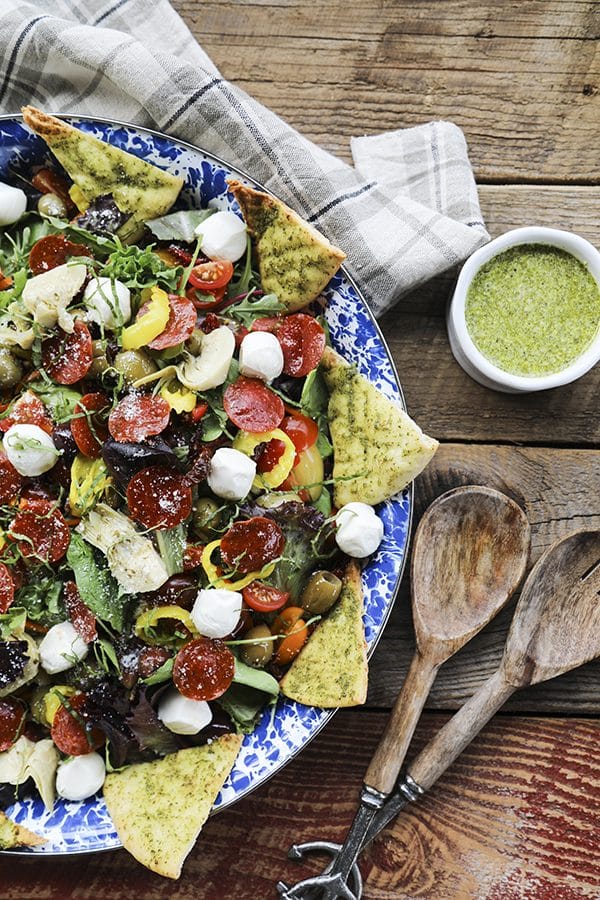 Supreme Pizza Salad: this salad is no boring, average salad. Mixed greens are tossed with crisped pepperoni, pesto pita chips, artichoke hearts, mini mozzarella balls, marinated olives, cherry tomatoes, sun dried tomatoes, pepperoncini, Parmesan cheese and a flavourful pesto vinaigrette.