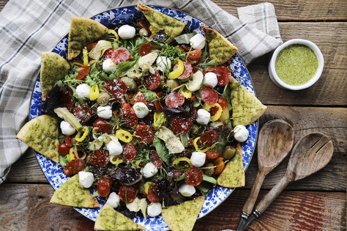 Supreme Pizza Salad: this salad is no boring, average salad. Mixed greens are tossed with crisped pepperoni, pesto pita chips, artichoke hearts, mini mozzarella balls, marinated olives, cherry tomatoes, sun dried tomatoes, pepperoncini, and a flavourful pesto vinaigrette.