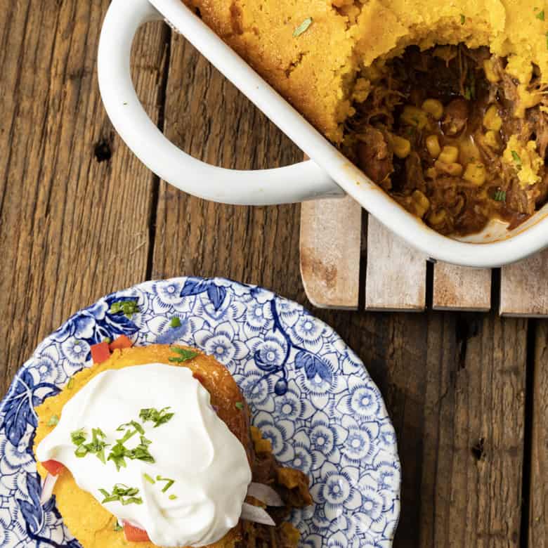 This satisfying, comforting Pulled Pork Casserole lets you get a dinner the whole family will love on the table even on busy weeknights. Saucy, succulent pulled pork with tender black beans and sweet corn is baked under golden brown cornbread in this easy casserole. Serve it alone or topped with all sorts of taco goodies like sour cream, grated cheese, onions, tomatoes, avocado, and taco sauce.