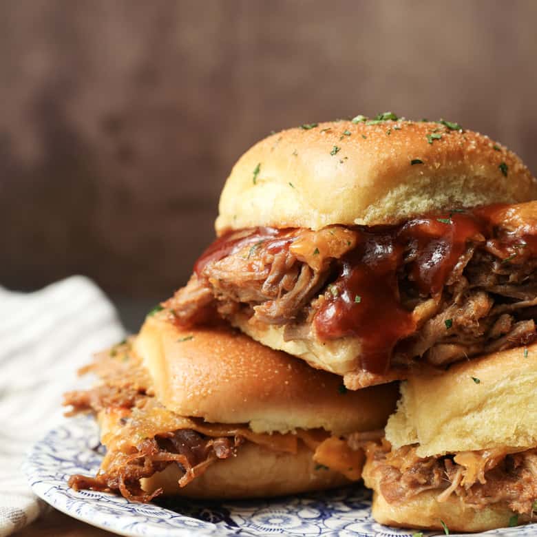 Easy Pulled Pork Sliders: Pillowy rolls filled with delicious, mouth-watering, tender pulled pork, bbq sauce, and cheese are brushed with melted butter, garlic, and herbs, then baked to toasty, melty perfection. They’re like the little black dress of the sandwich world and perfect for every occasion. Bonus: They're done in 30 minutes from start to finish!