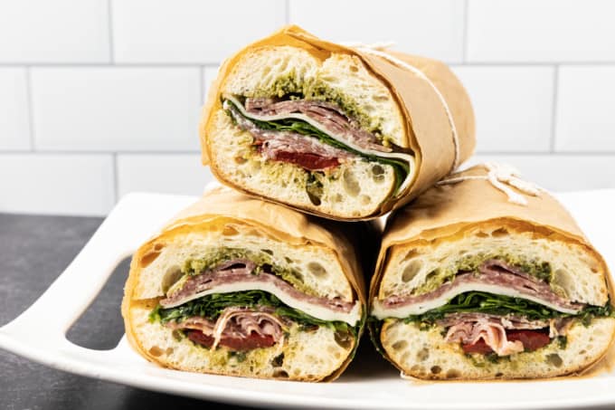 This is no ordinary Salami Sandwich; a crusty baguette is stuffed to bursting with a variety of salamis, roasted red pepper, pesto sauce, provolone cheese, fresh basil, and dressed arugula, then tightly wrapped and stashed in the refrigerator overnight. Then you can slice it all up and arrange it on a platter for a party or stretch it out for up to 5 days! And let me tell you, if you slice a little off of this every day for lunch with a cup of soup or bag of chips, you're going to feel very clever indeed. If you're feeling generous, pop it in a lunch bag for a school lunch that will make your kid the envy of the school.