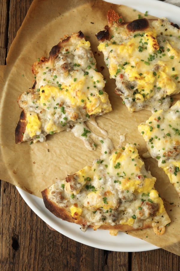 Hold onto your socks, because Sausage Gravy Breakfast Pizza just might knock them off! This ultimate comfort food mashup is coming soon to a breakfast, brunch (or dinner!) table near you. Chewy pizza crust is topped with cheesy, fluffy scrambled eggs, savoury, flavourful, creamy sausage gravy, and fragrant chives in this deliciously different pizza. Made on naan bread (or pre-baked pizza shells, homemade or purchased), these pizzas come together in just moments, too!