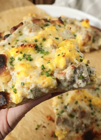 Hold onto your socks, because Sausage Gravy Breakfast Pizza just might knock them off! This ultimate comfort food mashup is coming soon to a breakfast, brunch (or dinner!) table near you. Chewy pizza crust is topped with cheesy, fluffy scrambled eggs, savoury, flavourful, creamy sausage gravy, and fragrant chives in this deliciously different pizza. Made on naan bread (or pre-baked pizza shells, homemade or purchased), these pizzas come together in just moments, too!