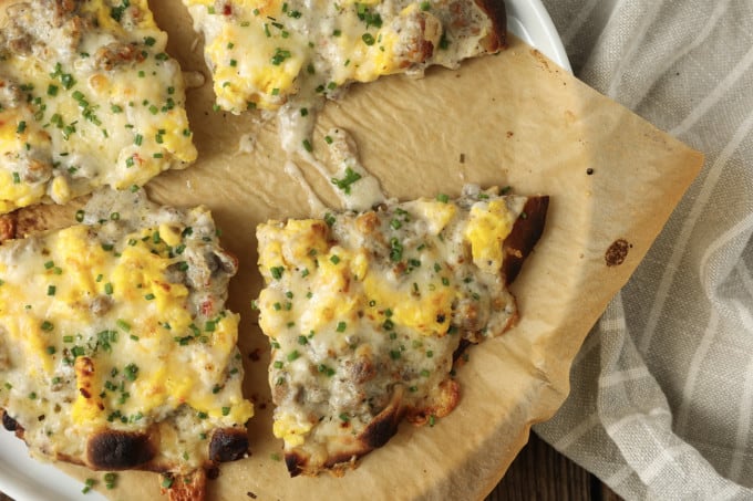 Hold onto your socks, because Sausage Gravy Breakfast Pizza just might knock them off! This ultimate comfort food mashup is coming soon to a breakfast, brunch (or dinner!) table near you. Chewy pizza crust is topped with cheesy, fluffy scrambled eggs, savoury, flavourful, creamy sausage gravy, and fragrant chives in this deliciously different pizza. Made on naan bread (or pre-baked pizza shells, homemade or purchased), these pizzas come together in just moments, too!